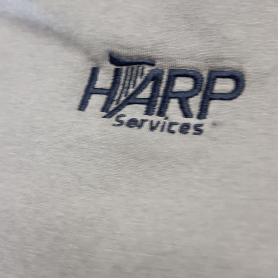 Embroidered HARP Services logo on a work shirt